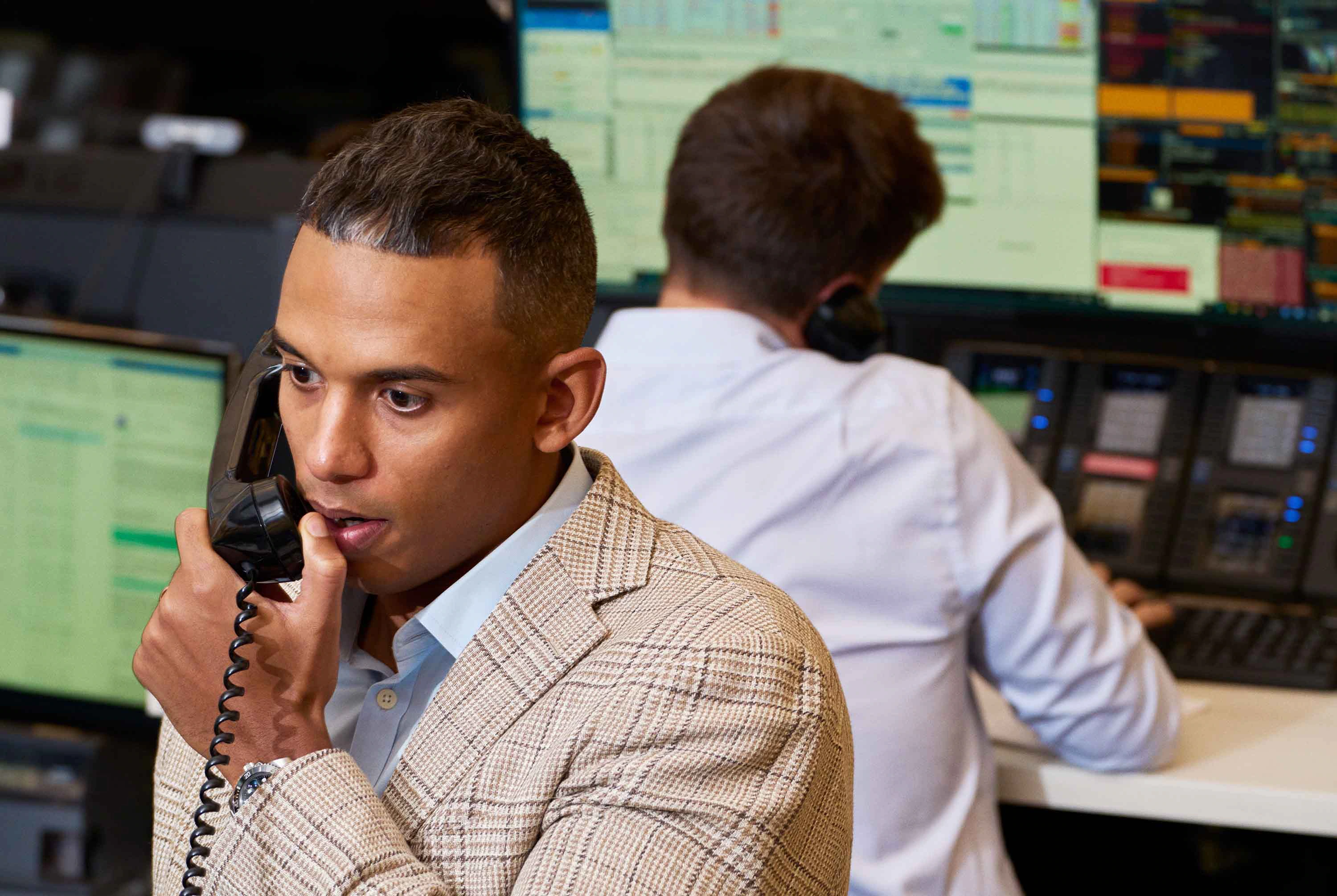 A person managing their finances on a laptop and phone, with a  Monarch Gray Haven card nearby